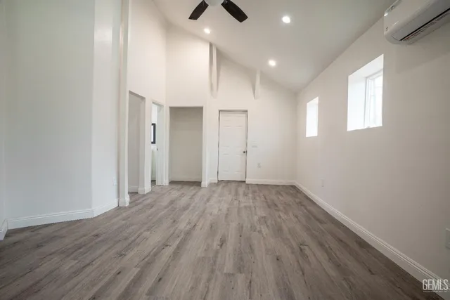an empty room with wooden floor ceiling fan and windows