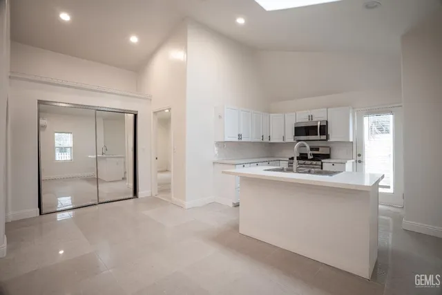 a large white kitchen with stainless steel appliances granite countertop a sink and cabinets