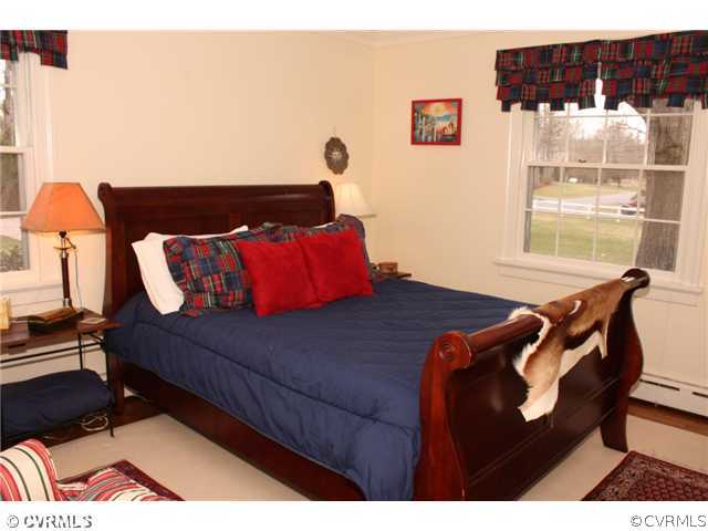 9100 River Road Henrico, VA 23229 - Photo 11 of 24 a bed sitting in a bedroom next to a window with wooden floor