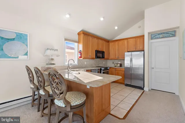 a kitchen with granite countertop kitchen island stainless steel appliances a sink stove and refrigerator