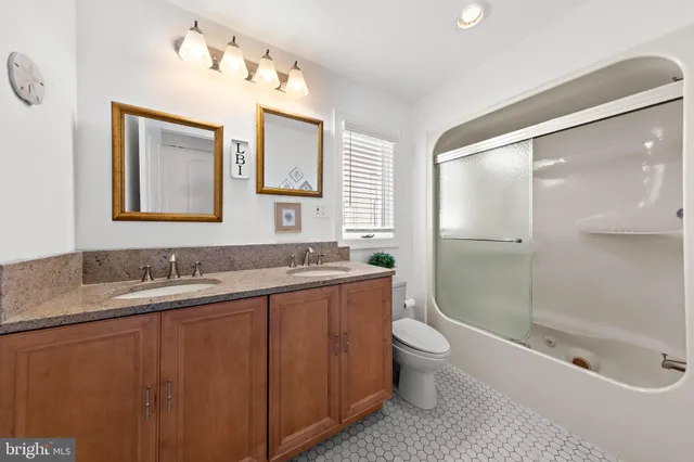 a bathroom with a granite countertop sink a toilet a mirror and shower