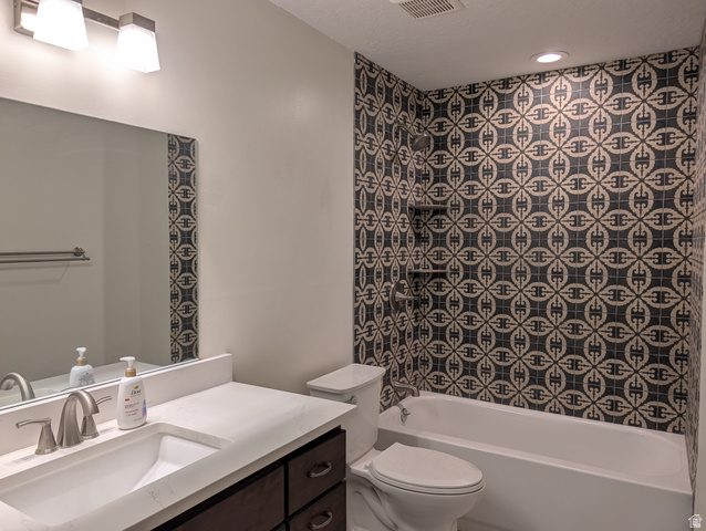 171 South Mustang Road East Grantsville, UT 84029 - Photo 21 of 41 Bathroom featuring a patterned tile shower surround, integrated shower shelving, white bathtub, and a single-sink vanity