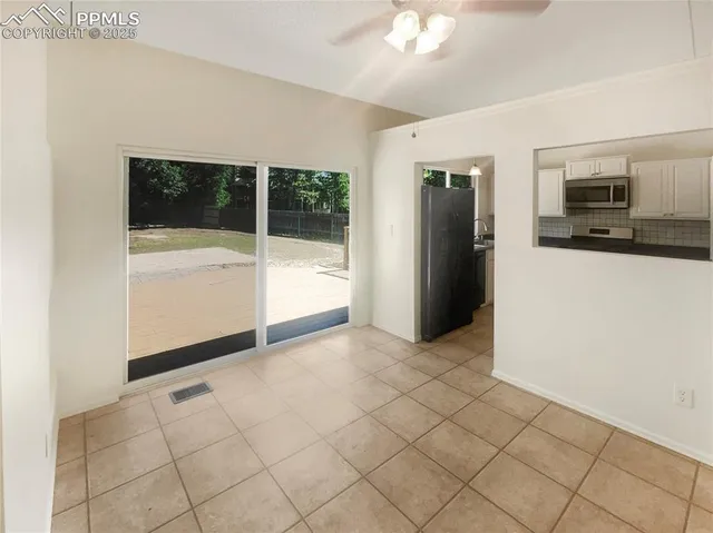 a view of a refrigerator in kitchen and an empty room