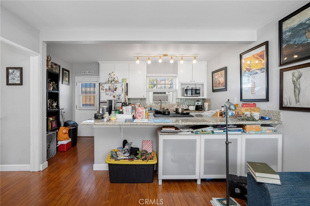 257 5th Street Seal Beach, CA 90740 - Photo 17 of 49 a kitchen with a sink dishwasher a dining table and chairs with wooden floor
