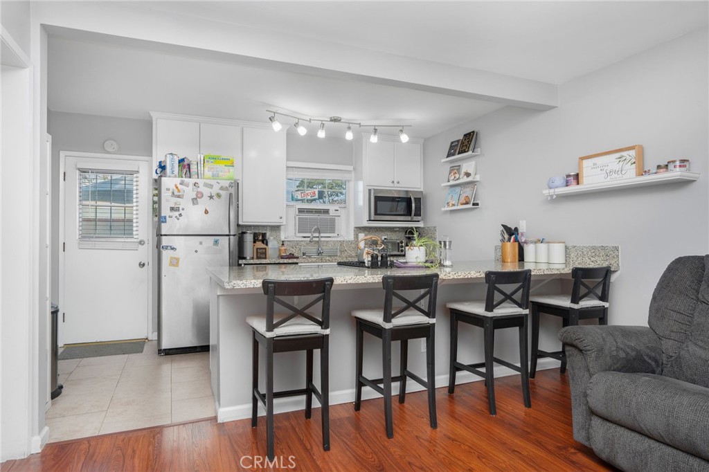 257 5th Street Seal Beach, CA 90740 - Photo 25 of 49 a kitchen with stainless steel appliances granite countertop a dining table chairs refrigerator and sink
