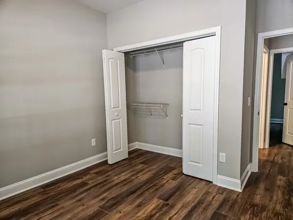 a view of an empty room with wooden floor and closet