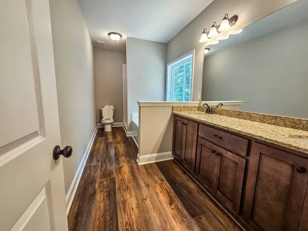 a view of a bathroom with a sink a mirror and a hardwood
