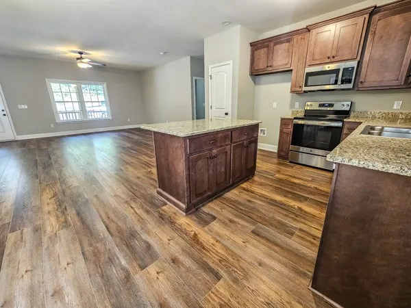 a kitchen with stainless steel appliances granite countertop a sink a stove top oven a refrigerator cabinets and wooden floor