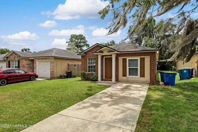 a front view of a house with a garden and trees