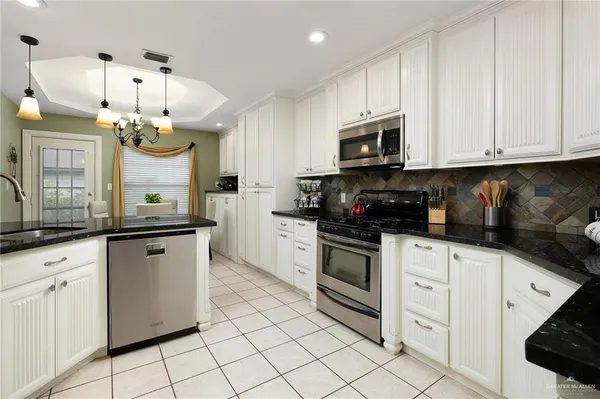 a kitchen with granite countertop white cabinets and white appliances