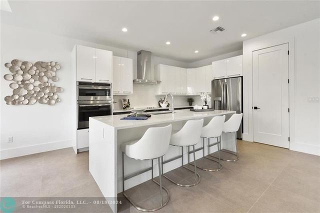 a large kitchen with kitchen island white cabinets and stainless steel appliances