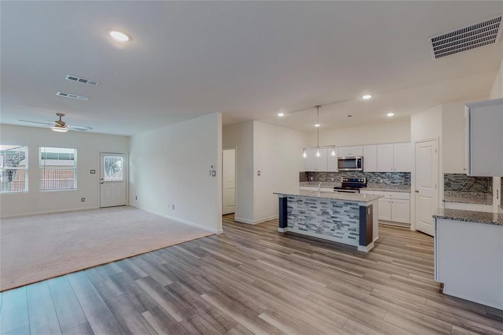 407 Madison Way Princeton, TX 75407 - Photo 39 of 40 Kitchen featuring open floor plan, a ceiling fan, light wood finished floors, backsplash, and stone countertops