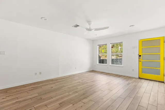 an empty room with wooden floor and windows