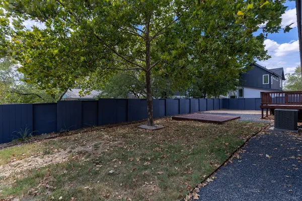 a view of a backyard with large trees and wooden fence