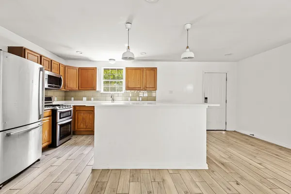 a kitchen with kitchen island wooden floors appliances and center island