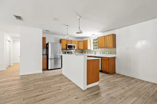 a kitchen with stainless steel appliances granite countertop a stove a refrigerator a sink dishwasher and white cabinets with wooden floor