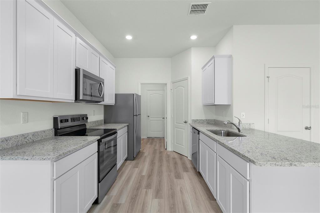13320 Tula Loop Astatula, FL 34705 - Photo 4 of 22 a kitchen with stainless steel appliances granite countertop a stove a sink and a refrigerator