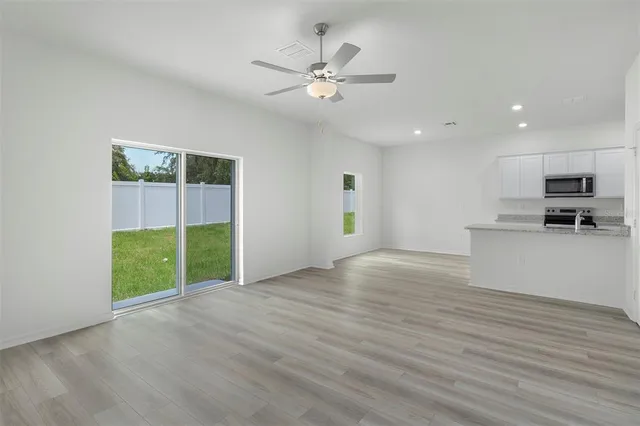 a view of an empty room with a window and kitchen view