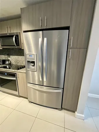 a metallic refrigerator freezer and a stove sitting inside of a kitchen