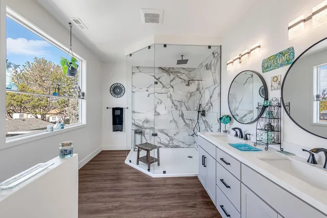 a spacious bathroom with double vanity sink a two mirror a window and a shower