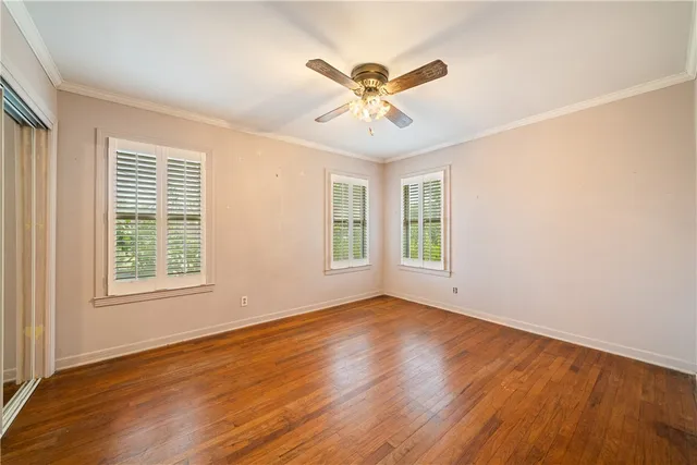 a view of an empty room with a window and wooden floor
