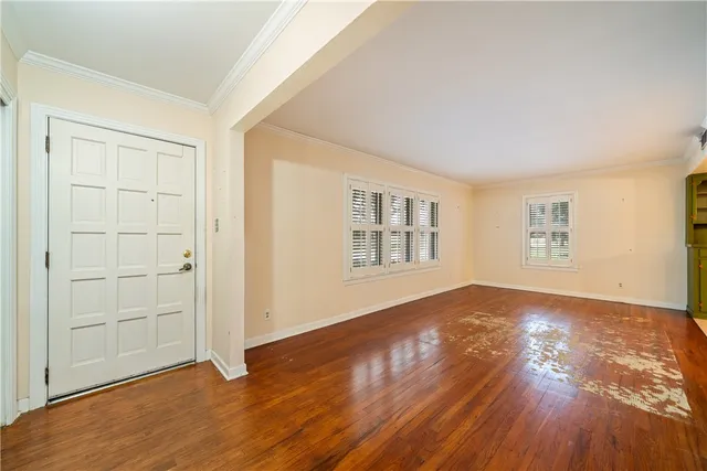 an empty room with wooden floor closet and windows