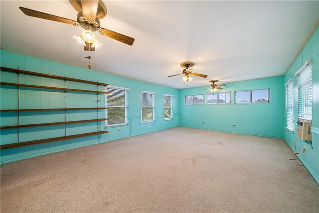 a view of an empty room with a window and a chandelier fan
