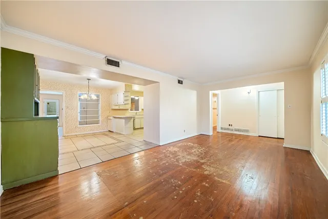 a view of an empty room with wooden floor and a kitchen