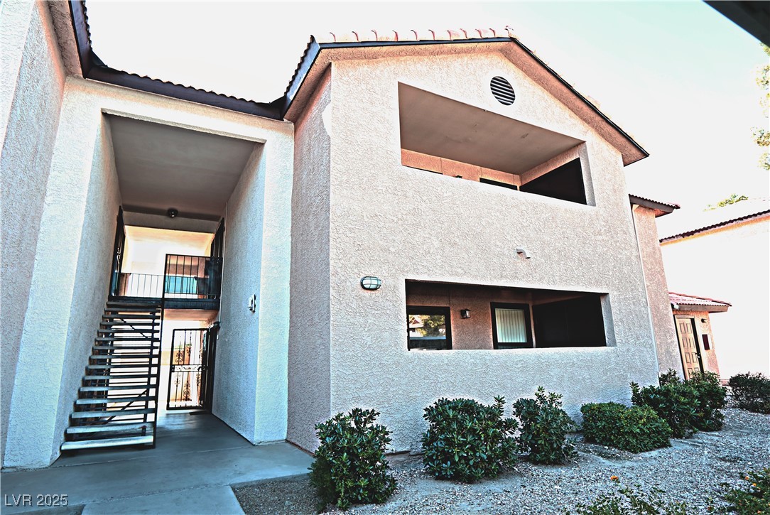 2451 North Rainbow Boulevard, Unit 1020 Las Vegas, NV 89108 - Photo 3 of 14 View of front of property with stucco siding, a tile roof, stairs, and a balcony