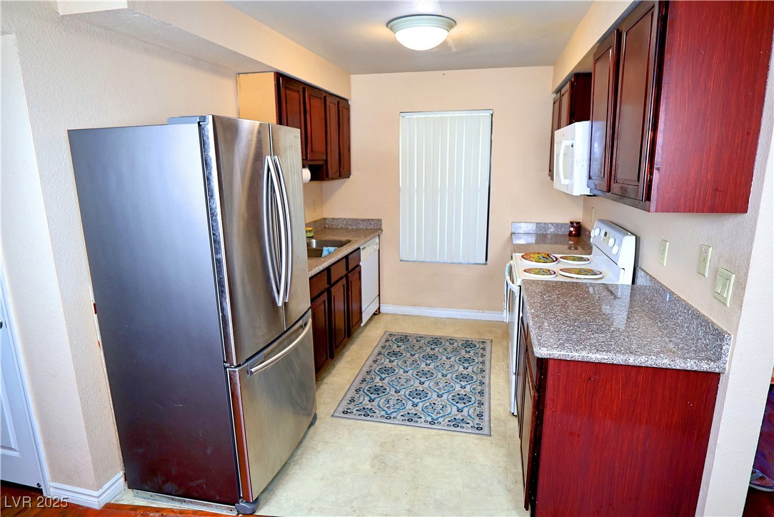 2451 North Rainbow Boulevard, Unit 1020 Las Vegas, NV 89108 - Photo 8 of 14 Kitchen with white appliances, dark stone countertops, and reddish brown cabinets