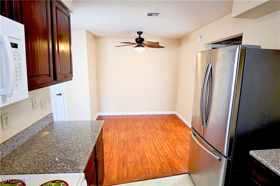 2451 North Rainbow Boulevard, Unit 1020 Las Vegas, NV 89108 - Photo 9 of 14 Kitchen featuring white appliances, light wood-style floors, ceiling fan, and dark stone countertops