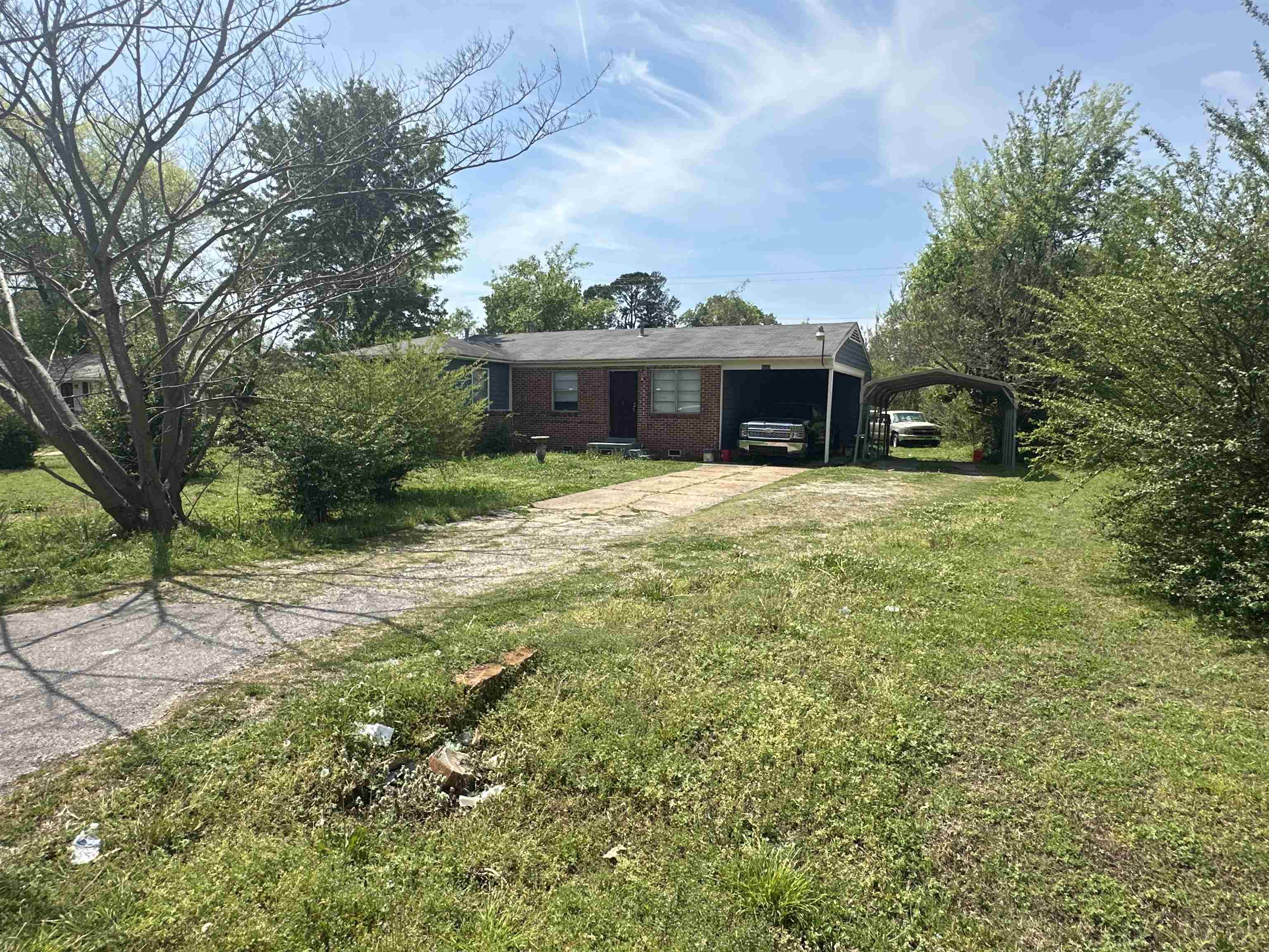 View of front facade with driveway, brick siding, and a front yard