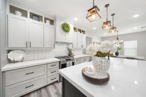 a kitchen with a stove a sink and a dining table with wooden floor