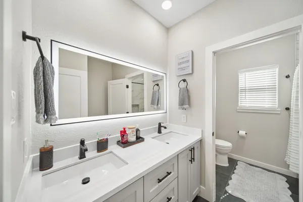 a bathroom with a sink a toilet and shower a mirror
