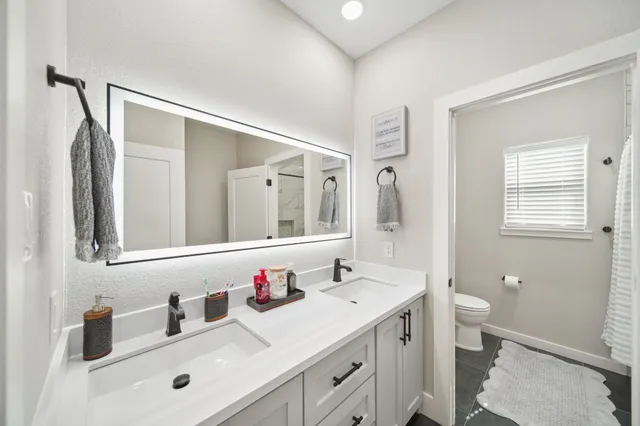 a bathroom with a sink a toilet and shower a mirror