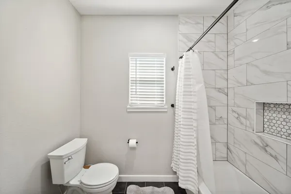 a white toilet sitting next to a bath tub