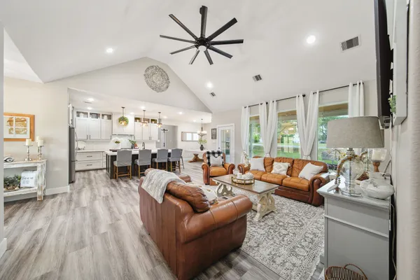 a living room with furniture kitchen view and a large window