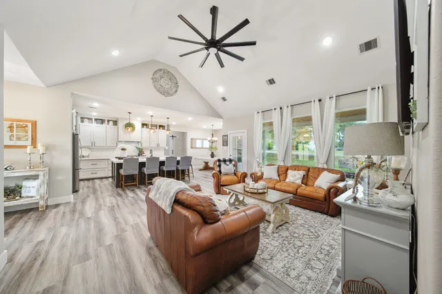a living room with furniture kitchen view and a large window