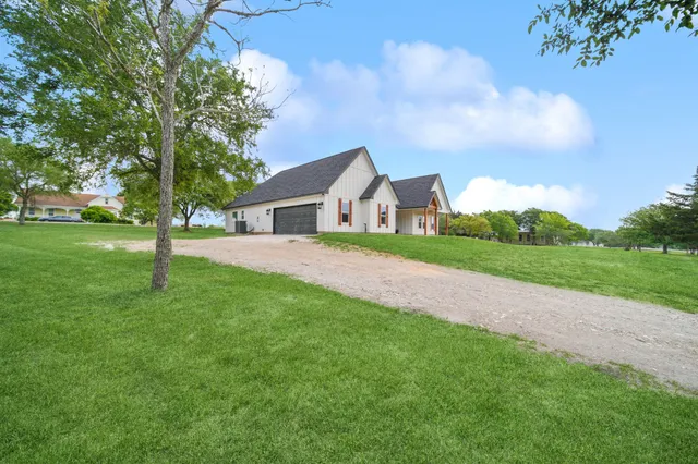 a view of house with a big yard and large trees