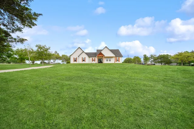a view of a house with a big yard and large trees