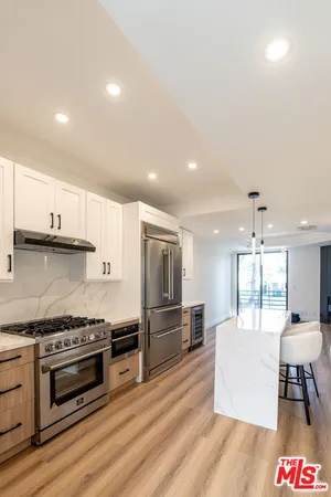 a kitchen with stainless steel appliances a stove a sink cabinets and wooden floor