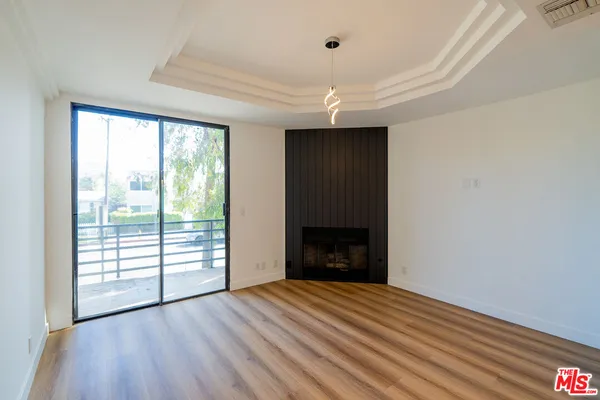 an empty room with wooden floor fireplace and windows