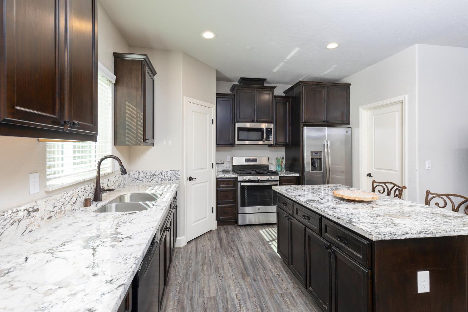 1374 South Enns Avenue Reedley, CA 93654 - Photo 16 of 48 a kitchen with granite countertop kitchen island stainless steel appliances a sink stove refrigerator and cabinets