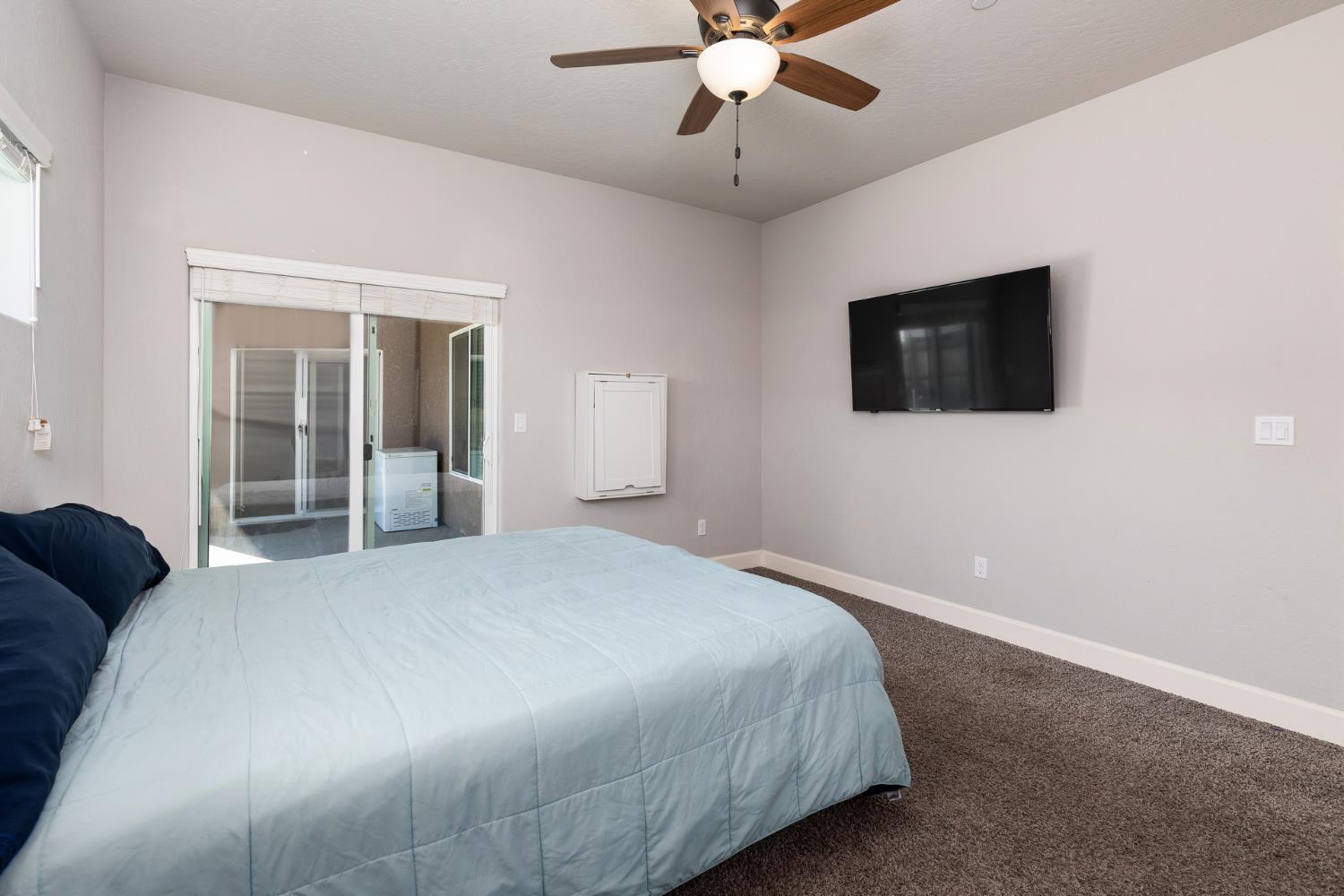 1374 South Enns Avenue Reedley, CA 93654 - Photo 22 of 48 a bedroom with a large bed and a flat screen tv