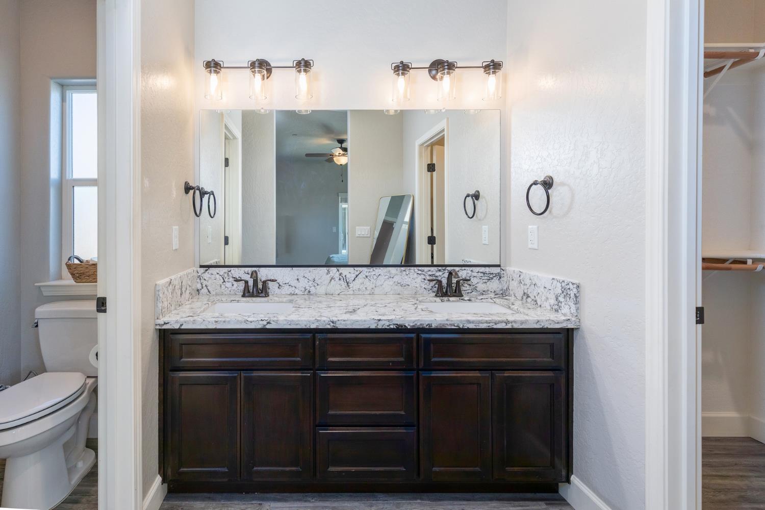 1374 South Enns Avenue Reedley, CA 93654 - Photo 23 of 48 a bathroom with a granite countertop sink a toilet and a mirror