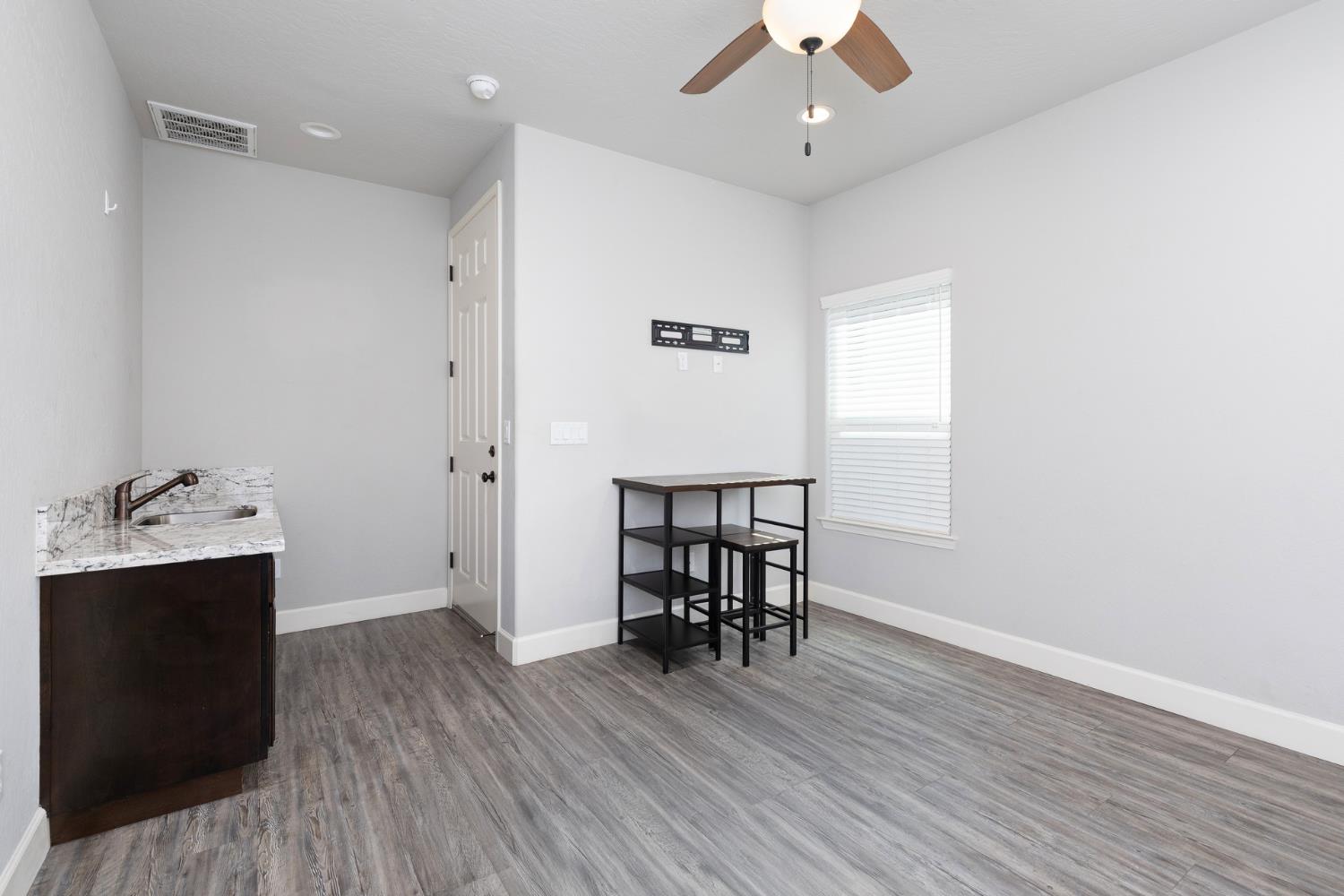 1374 South Enns Avenue Reedley, CA 93654 - Photo 46 of 48 an empty room with wooden floor a chandelier fan and windows