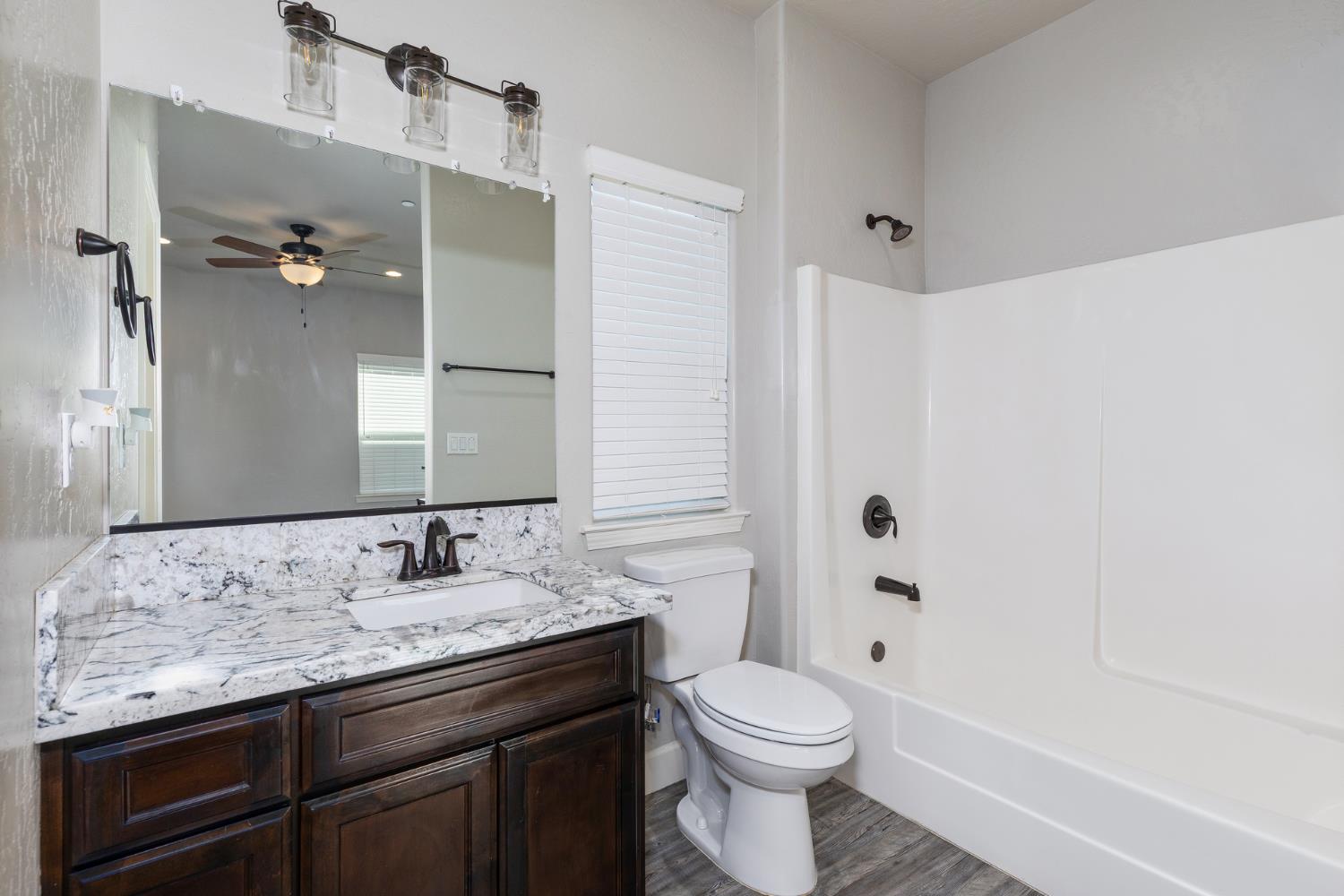 1374 South Enns Avenue Reedley, CA 93654 - Photo 48 of 48 a bathroom with a granite countertop sink toilet and shower