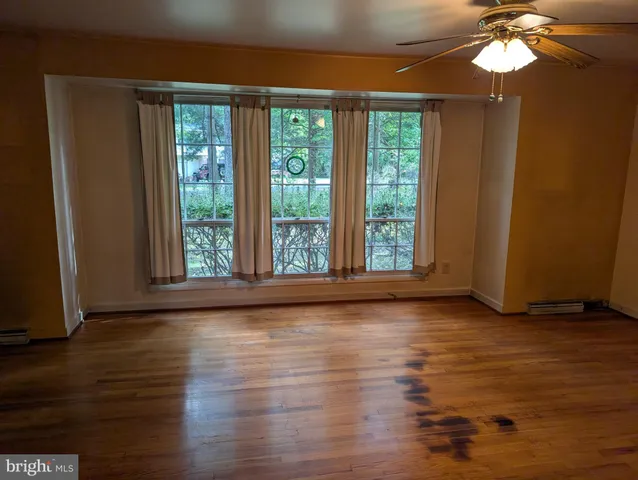 an empty room with wooden floor fan and window