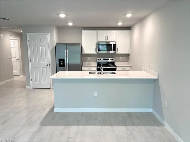 a kitchen with stainless steel appliances a refrigerator sink stove microwave and cabinets