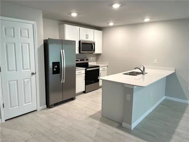 a kitchen with stainless steel appliances a refrigerator sink and microwave